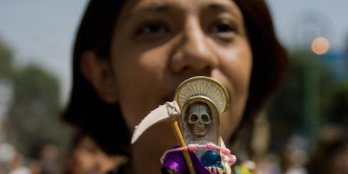 A devotee holds an image of the 'Santa Muerte' (Holy Death), at Tepito shantytown, in Mexico City, on April 5, 2009. The cult of this pseudo-religious skeletal image, also known as 'La Sant?sima', 'Dona Sebastiana', 'Little White Girl' or 'The Skinny Girl', is thought to date back to pre-Columbian times. The Holy Death currently has some two million faithfuls in Mexico who ask to the authorities to be recognized as a separate religion. AFP PHOTO/Alfredo Estrella (Photo credit should read ALFREDO ESTRELLA/AFP/Getty Images)